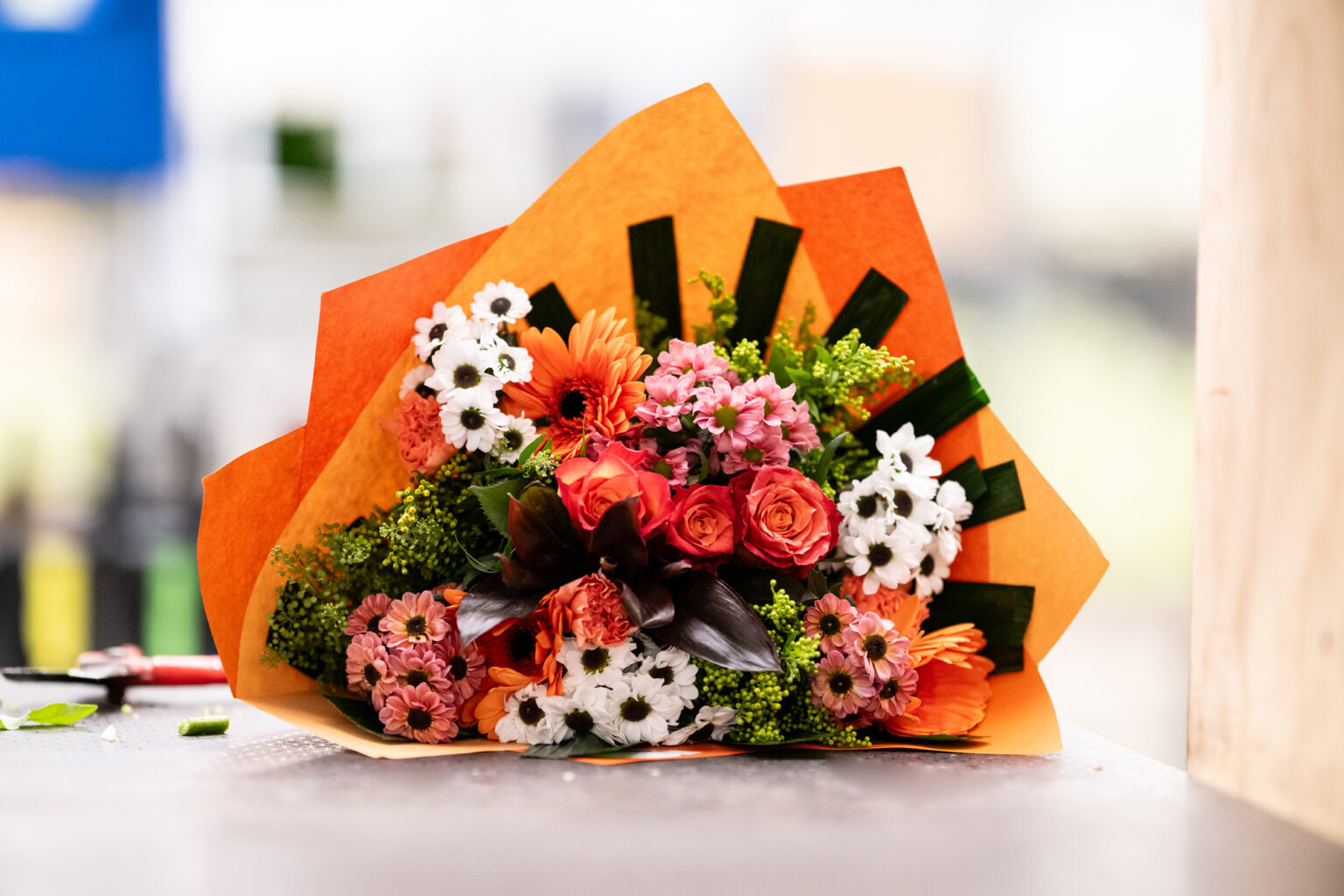 Bouquet de roses et gerberas dans un emballage orange réalisé par Europlantes