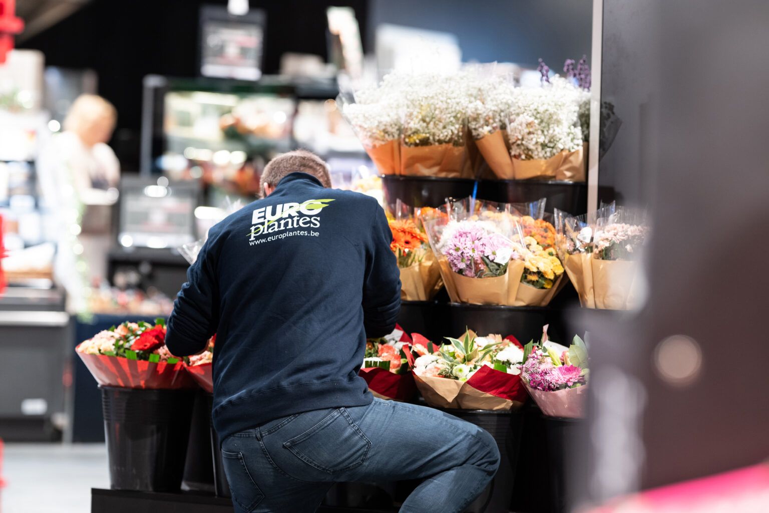 Employé Europlantes réassortissant le rayon fleurs d’un magasin